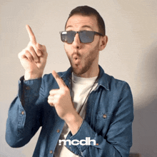 a man wearing sunglasses and a denim shirt has the word mcdh on the bottom right