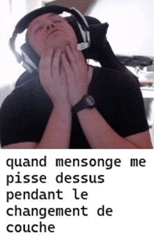 a man wearing headphones and a watch is laying down with his hands on his face