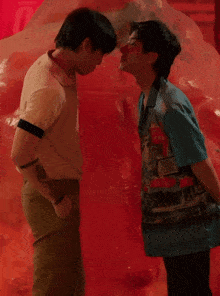 two men are looking at a large red object with a red background