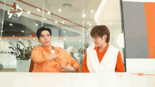 two men are talking to each other in front of a glass wall with a sticker that says ' a ' on it