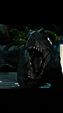 a dinosaur with its mouth open is standing in the dark .
