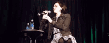 a woman is sitting on a stage holding a microphone and dancing .