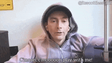 a man wearing a hoodie and a hat is sitting in a chair and talking .