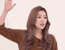 a woman in a brown sweater is waving her hand .