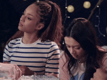 a woman in a striped shirt sits next to a woman in a pink shirt