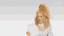 a drag queen is holding a piece of paper in her hand and screaming .