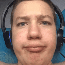 a man wearing headphones looks at the camera with a sad look on his face