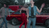 a man and a woman are dancing in front of a red car that says bfgoodrich on it