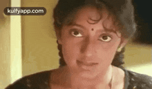 a woman with a bindi on her forehead is looking at the camera with a serious look on her face .