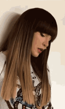 a woman with long hair and bangs is wearing a white shirt with a snake on it
