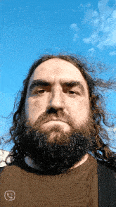 a man with a beard and long hair is wearing a brown shirt