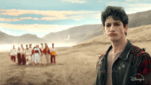 a man with green hair is standing in front of a group of people wearing a disney + jacket