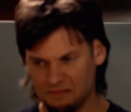 a man with long hair and a beard is making a face