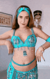 a woman in a blue costume is dancing in front of a statue