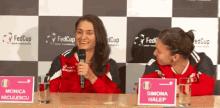 two women sitting at a table with a sign that says simona halep on it