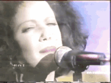 a close up of a woman singing into a microphone on a tv screen .