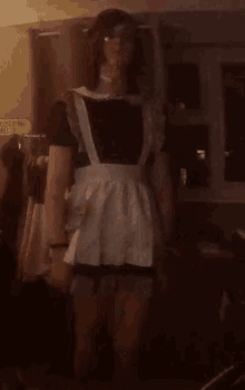 a woman in a maid costume is standing in a room holding hands .