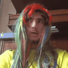 a man wearing a yellow shirt and a rainbow colored wig
