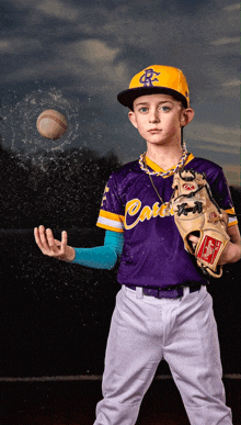 a young boy in a catchers uniform is holding a baseball in his hand