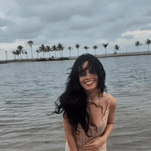 a woman in a white dress is standing in the water and smiling