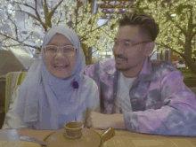 a man in a tie dye shirt is pointing at a woman who is laughing