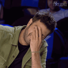a man covering his face with his hand in front of an ad for got talent spain