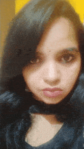 a close up of a woman 's face with a yellow wall behind her