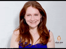 a woman in a blue top is smiling in front of a sign that says lillee jean productions