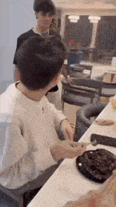 a man is sitting at a table eating a chocolate cake with a spoon .