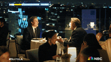 a group of people sitting at a table with a nbc logo on the bottom right