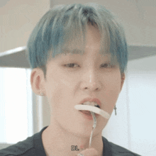 a man with blue hair is eating a piece of food with a fork