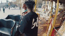 a man standing in front of a merry go round wearing a black shirt with the number 30 on the back