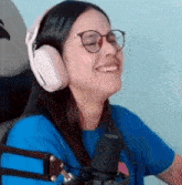a woman wearing headphones and glasses is sitting in front of a microphone .