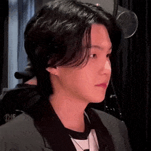 a close up of a person 's face with black hair and a black jacket .