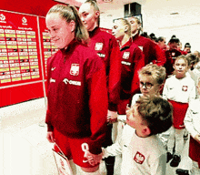a group of people wearing red jackets and shorts with the word orlen on them