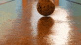 a bowling ball is on a wooden floor with the sun shining on it
