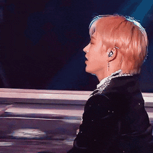 a man with blonde hair is wearing ear buds