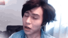 a young man with short hair is making a funny face with his eyes closed and his mouth open .