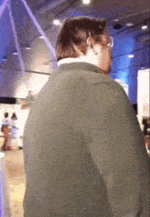 a man wearing glasses and a green jacket is standing in a room
