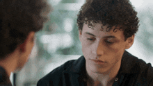 a young man with curly hair looks down at something