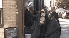 a woman taking a picture of another woman in front of a sign that says greens juice