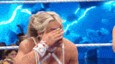 a woman in a wrestling ring is covering her face with her hands