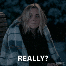 a woman is wrapped in a plaid blanket and says really