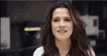 a woman with long hair is making a funny face and smiling .