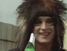 a man with a feathered hat is smiling and holding a bottle