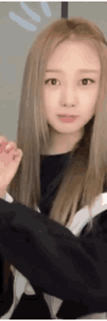 a close up of a woman 's face with long blonde hair and a black shirt .