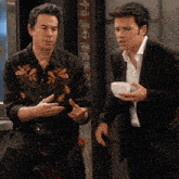 a man wearing a cowboy shirt is talking to another man in a suit