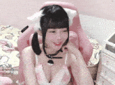 a girl wearing a cat ear headband is sitting on a pink chair
