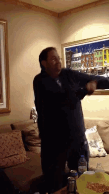 a man is dancing in a living room in front of a picture