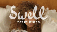 a woman with curly hair is laying on a bed with the word swell written above her